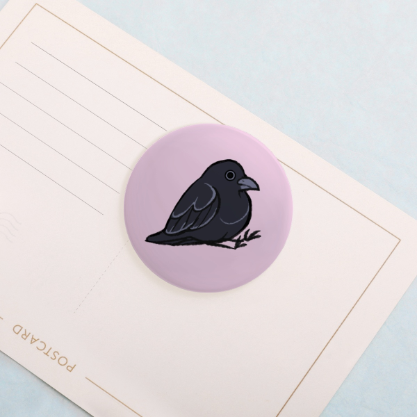Raven sitting on his butt button pin